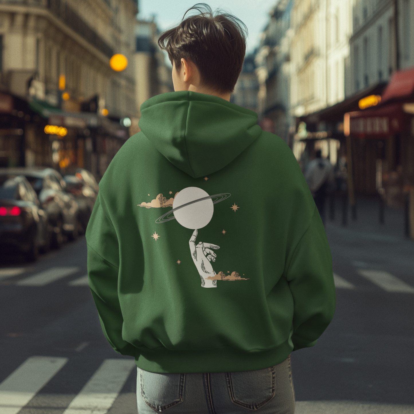 Person wearing a green hoodie with a unique design on the back, standing on a city street.