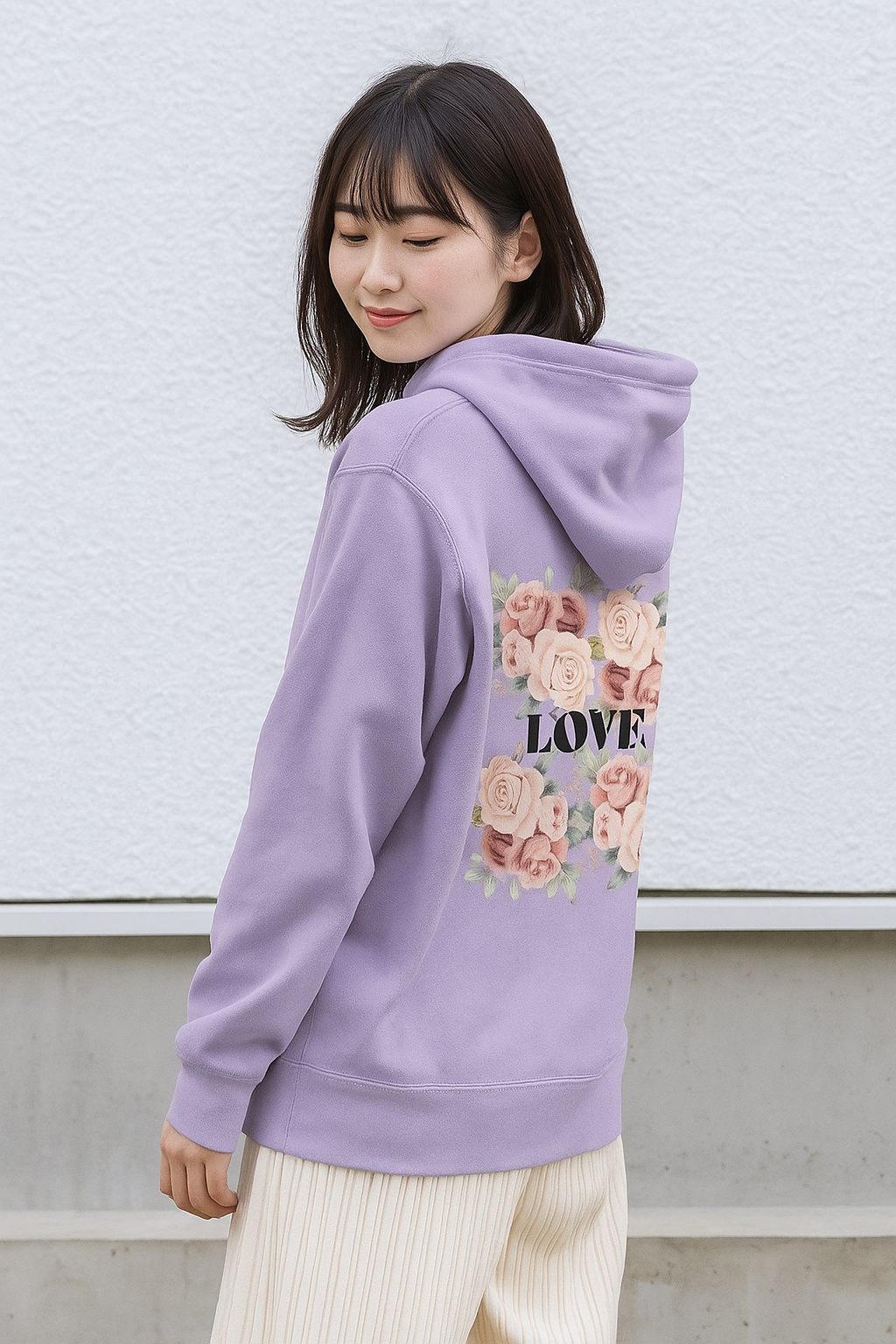 Person wearing a purple hoodie with floral designs and 'LOVE' text on the back, standing against a light-colored wall.
