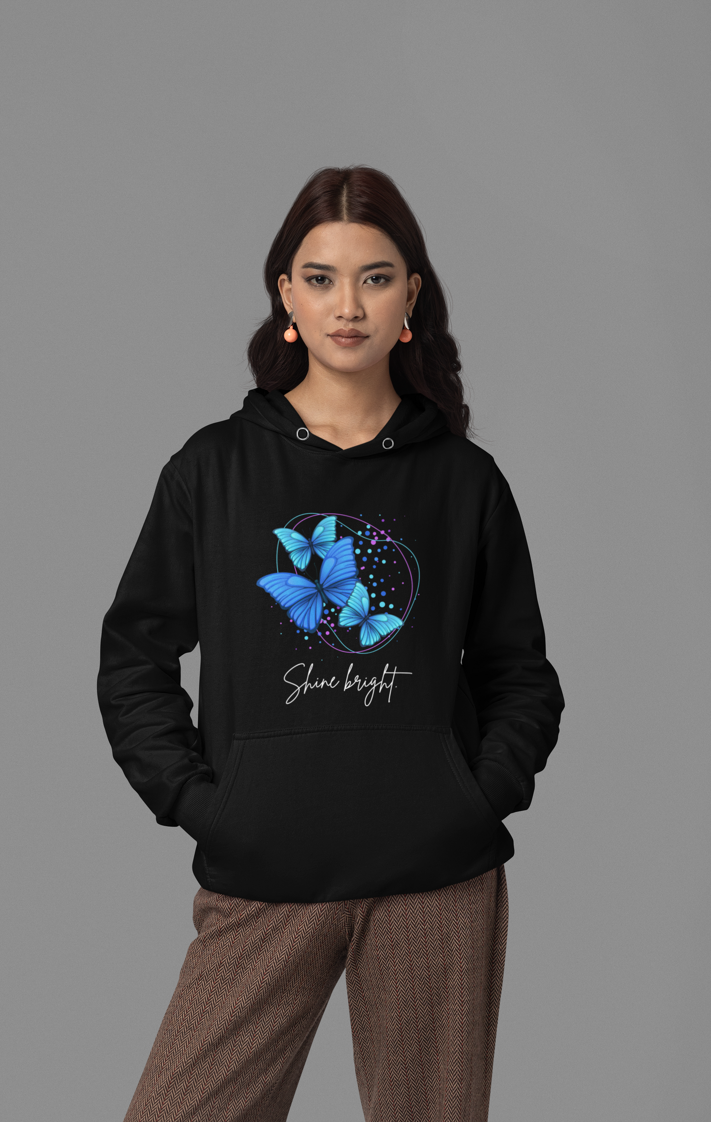 A woman wearing a black hoodie with a design and text on the front.