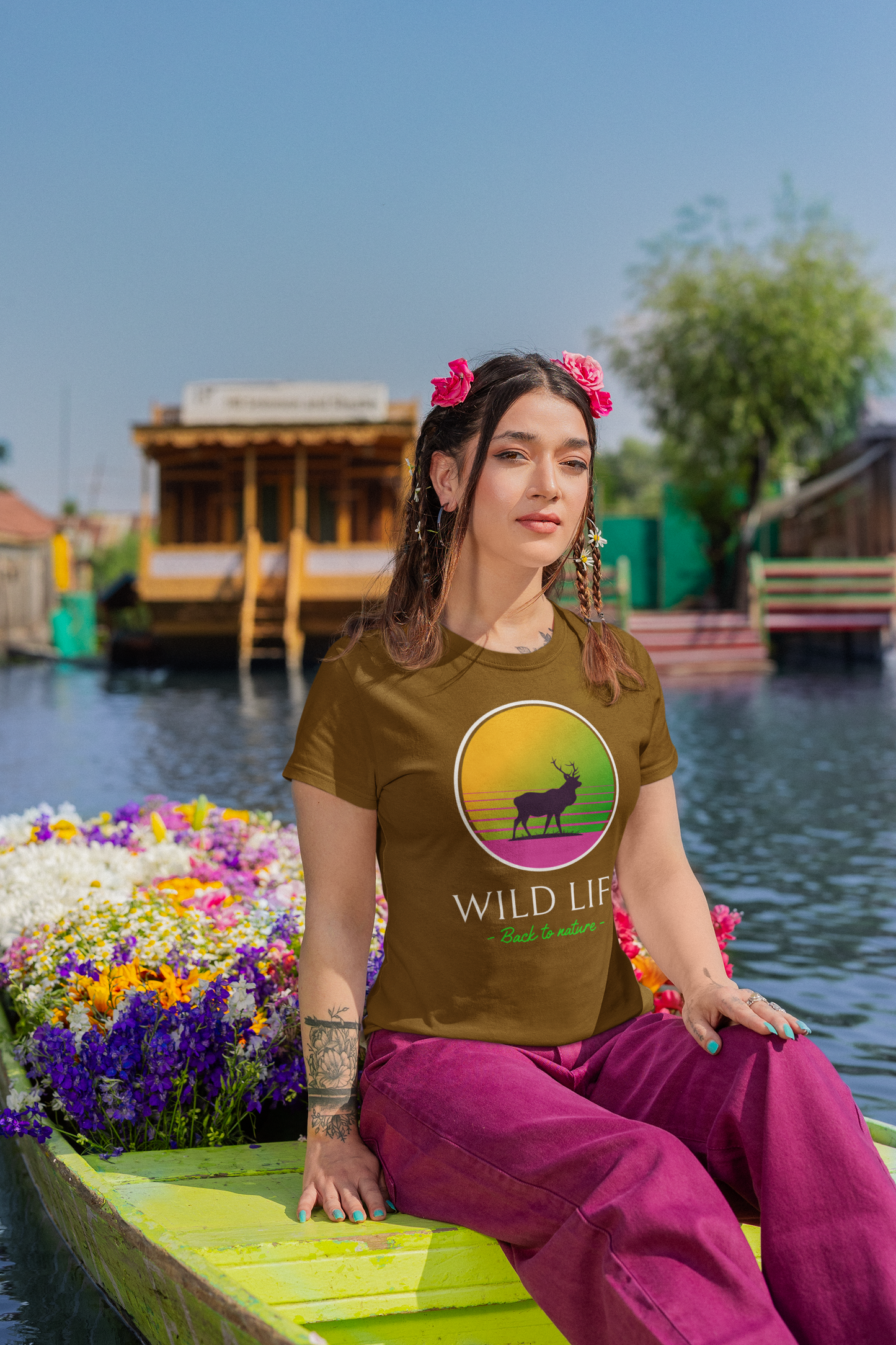 Woman sitting on a boat with a scenic background wearing a 'Wild Life' t-shirt.