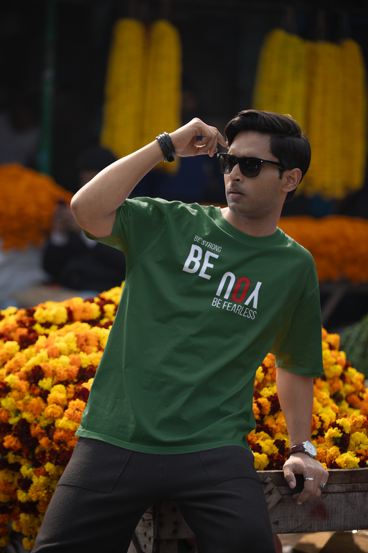 Man wearing a green t-shirt with text, standing in front of flower arrangements.