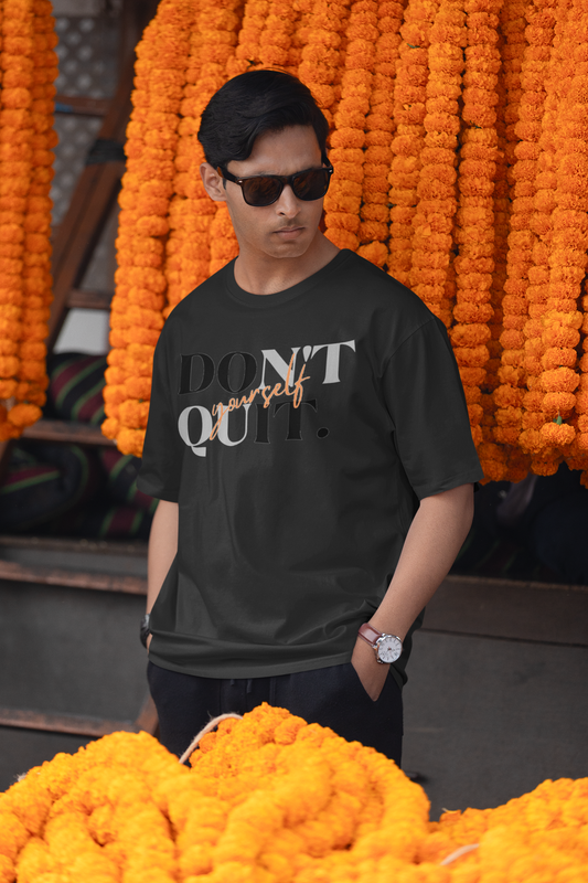 Man wearing a black t-shirt with text standing among orange marigold flowers.
