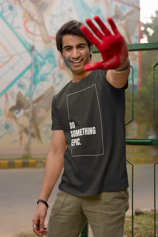 Man wearing a black t-shirt with 'DO SOMETHING EPIC.' text, holding up a red glove outdoors.