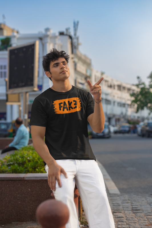 Man wearing a black t-shirt with 'FAKE' logo in an urban setting