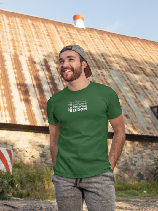 Man wearing a green t-shirt with 'FREEDOM' text, standing in front of a rustic building.
