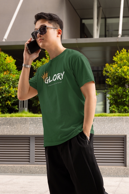 Person wearing a green t-shirt with 'GLORY' printed on it, talking on a phone outdoors.