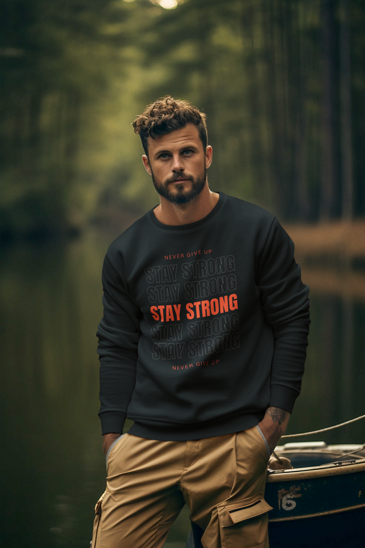 Man wearing a black sweatshirt with red text Saying Stay Strong standing in a forest