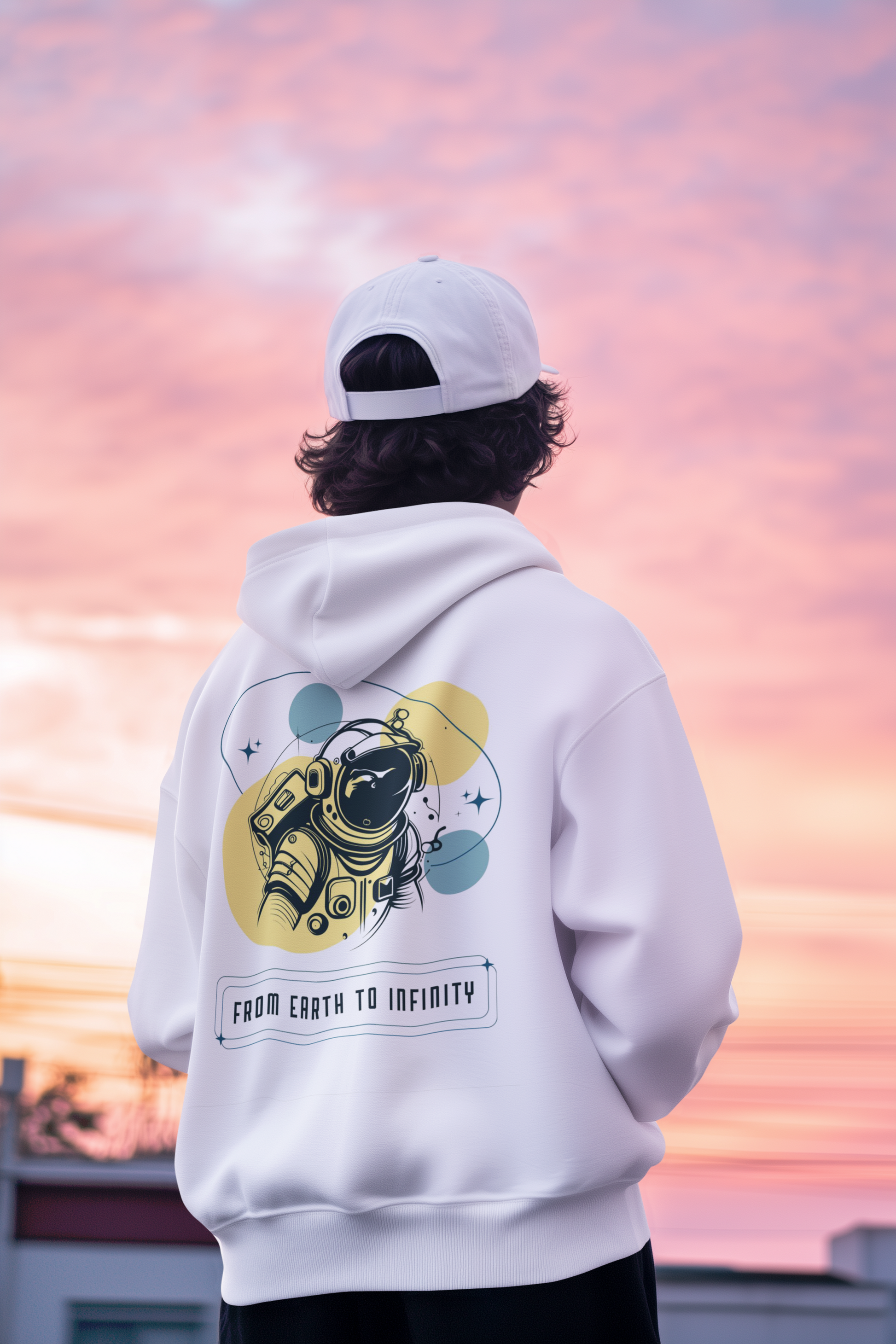 Person wearing a white hoodie with an astronaut graphic and text, standing against a colorful sky.