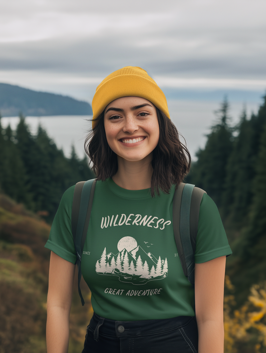 Woman wearing a green t-shirt with 'Wilderness Great Adventure' text and a yellow beanie in a forest setting.